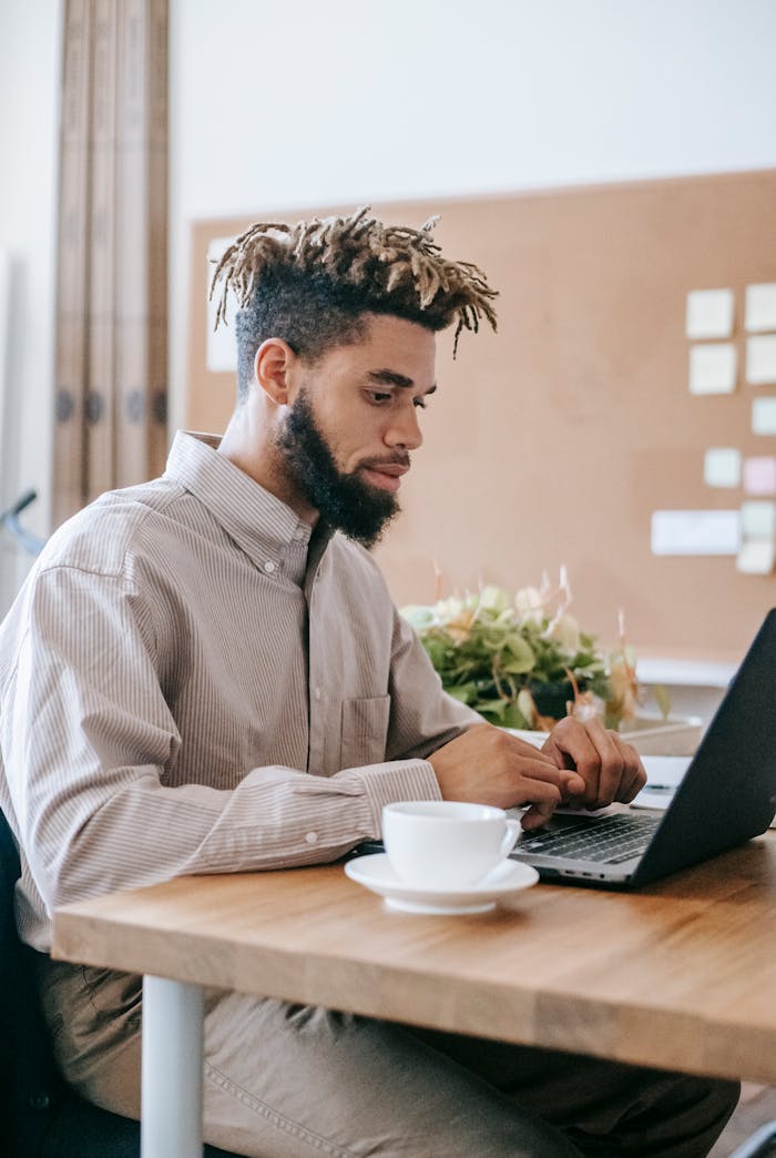 Man In Dress Shirt Sitting At The Table Using Laptop Computer